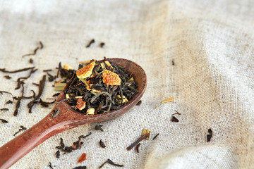 Closeup of a wooden spoon filled with scattered tea leaves, shallow depth of field, top view