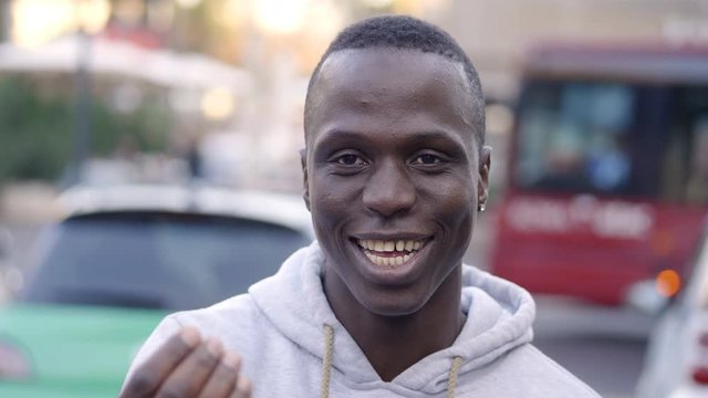 happy and smiling young African man talking with the camera in the street