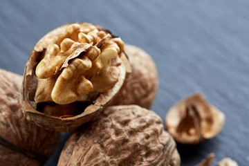 Top view close-up shot of cracked walnuts on dark background, shallow depth of field, macro