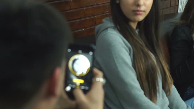 The boy is shuting his girlfriend with his smartphone