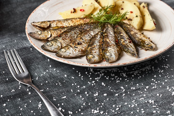 Traditional Spanish barbecue sardines with boiled potatoes, on a plate close up. horizontal