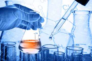 Flask in scientist hand with laboratory glassware background 