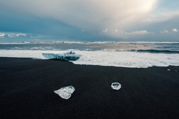 Ice on the black volcanic beach near Jokulsarlon glacier lagoon, winter Iceland. Detail of a glacial fragment of ice at black sand beach in beautiful evening light. © 1tomm