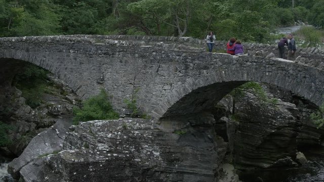 People walking and taking pictures on a bridge