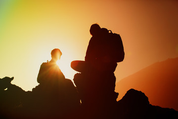 Silhouettes of father and son hiking in mountains at sunset