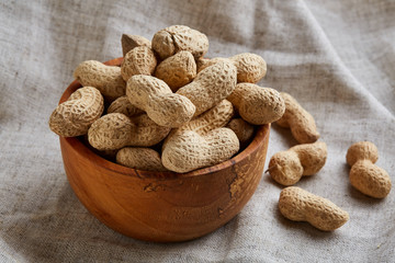 Unpeeled peanuts in ceramic bowl closeup, selective focus