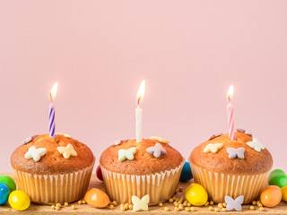 Birthday cupcakes with candles on the table. Pink background.