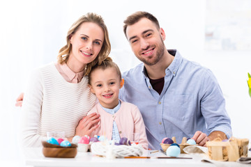 Obraz na płótnie Canvas Cheerful family smiling by painted eggs for Easter