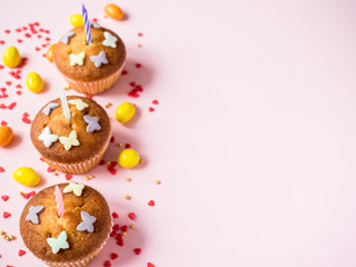 Birthday cupcakes with candles on the table. Pink background. Copy space