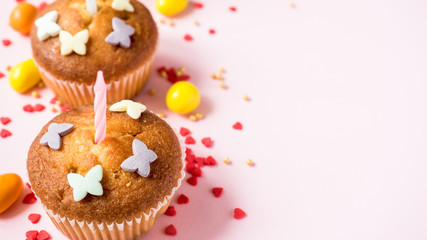 Birthday cupcakes with candles on the table. Pink background. Copy space