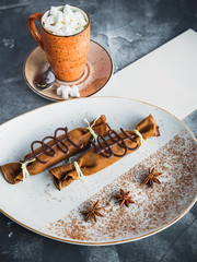 Chocolate pancakes with cinnamon, anise and cup of coffee with marshmallow. Food and paper menu