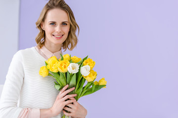 Smiling blonde woman holding bouquet of tulips for 8 march