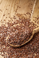 Wooden spoon with flax seeds on rustic background, top view, close-up, shallow depth of field, selective focus