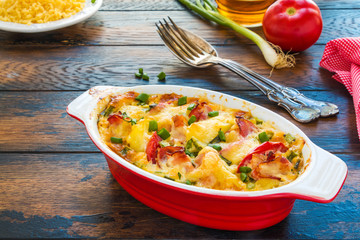 Casserole in Belgian style with smoked bacon, potatoes and cheese on the ooden rustic table.