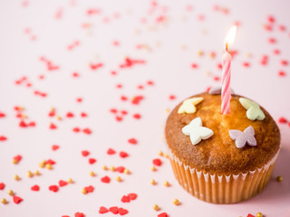 Birthday cupcakes with candles on the table. Pink background. Copy space