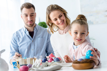 Celebrating family arranging painted eggs in nest for Easter decor