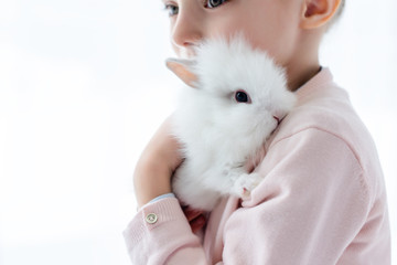 Adorable kid hugging white rabbit