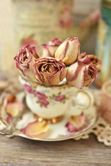 dried roses in vintage style porcelain cup