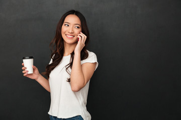 Smiling asian woman in t-shirt holding cup of coffee