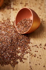 An overturned ceramic bowl with linseeds on a rustic background, close-up, shallow depth of field, selective focus