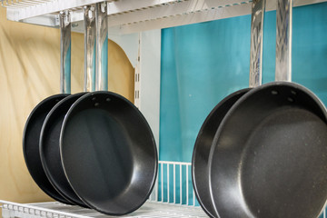 Empty frying pans hang on the shelf. Dishes. Cooking.