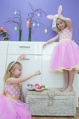 Easter holiday, home decoration. little girls in beautiful pink beaches having fun, decorating an apartment, decorative eggs