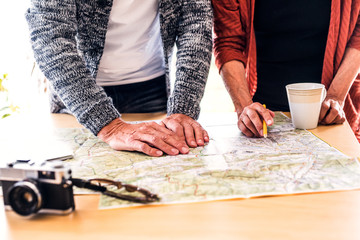 Senior couple with map at home, making plans.