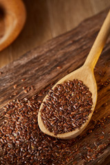 Wooden spoon with flax seeds on rustic background, top view, close-up, shallow depth of field, selective focus