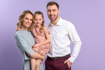 Smiling daughter and parents isolated on violet
