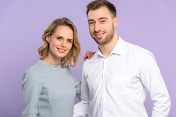 Young man and woman smiling isolated on violet