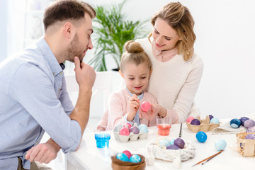 Obraz na płótnie Canvas Parents and daughter painting Easter eggs in different colors