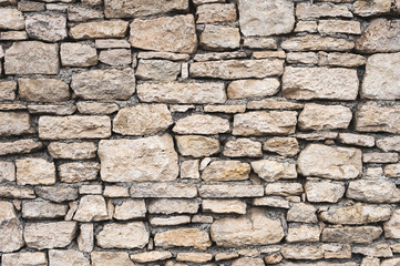 Close-up textured background is an irregular natural stone wall made of different stones without a cement-type bonding mixture. Medieval background