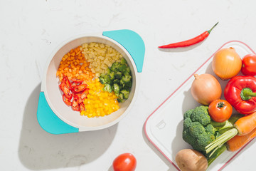 Chopped vegetables on pot and ingredients for tasty vegetarian cooking. Top view.