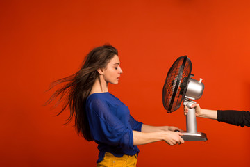 Portrait of a young beautiful woman with a fan in studio.
