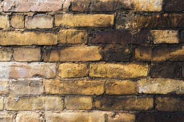 Textured background of old faded bricks stained with black oil. A brick gradient between dirty black and light yellow bricks. Grunge style