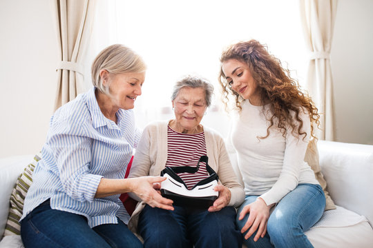 A teenage girl, mother and grandmother with VR goggles at home.