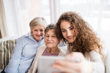 A teenage girl, mother and grandmother with smartphone at home.