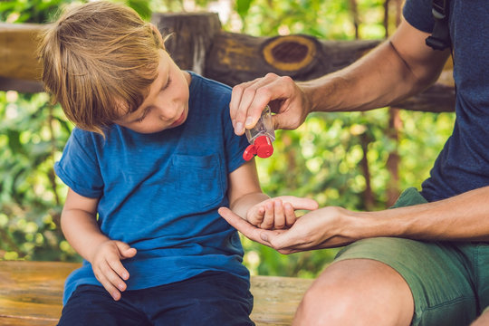 Father and son using wash hand sanitizer gel in the park before a snack