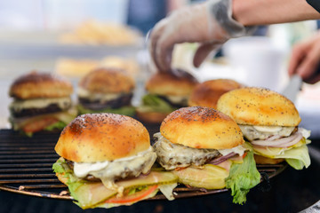 Chef making beef burgers outdoor on open kitchen international food festival event.