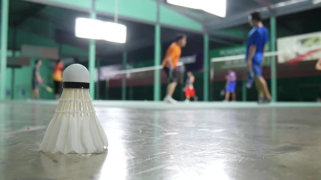 Shuttlecock laying on the floor with background of badminton practice