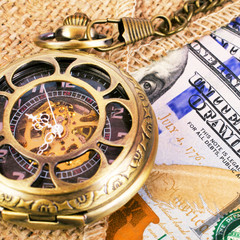 Fototapeta na wymiar Mechanical vintage pocket watch on burlap and US dollar banknotes. Time and wealthy concept. Square.