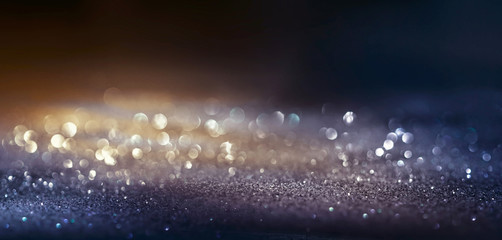 Glitter dark background black and golg color , de-focused, macro. Sparks fall and sparkle in ray of...