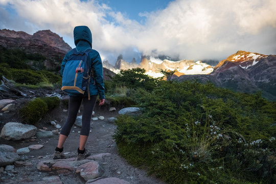 Hiker stands on the trail and enjoys mountains covered in clouds