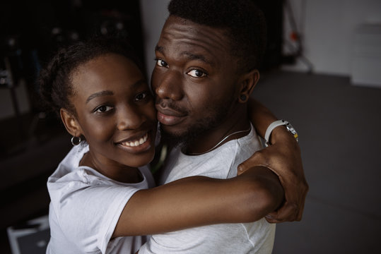 beautiful young african american couple hugging and smiling at camera