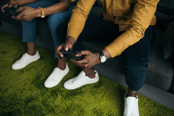 cropped shot of african american couple playing with joysticks together at home