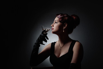 Dramatic portrait of a beautiful woman with glass of martini .