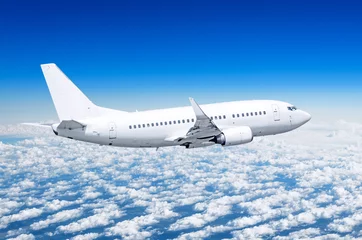 Fototapeten Passagierflugzeug fliegt auf einer Höhe über Wolken und blauem Himmel. © aapsky