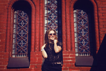 Pretty young woman model in fashion style posing over colorful red bricks background