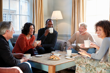 Fototapeta premium Group Of Middle Aged Friends Meeting Around Table In Coffee Shop