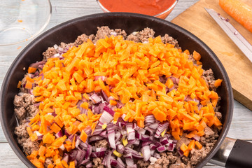Minced meat with onions and carrots for bolognese sauce roasted in a frying pan
